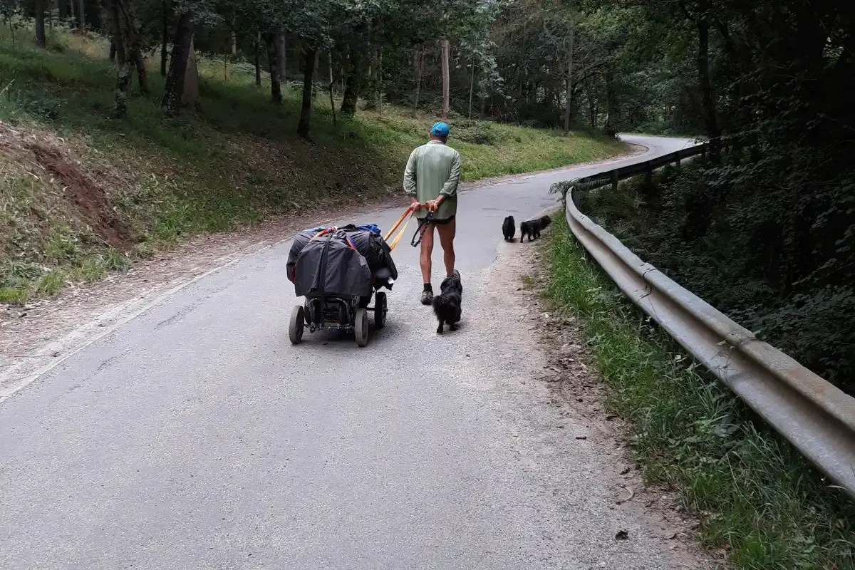 Peregrino con su perro subiendo una cuesta del Camino