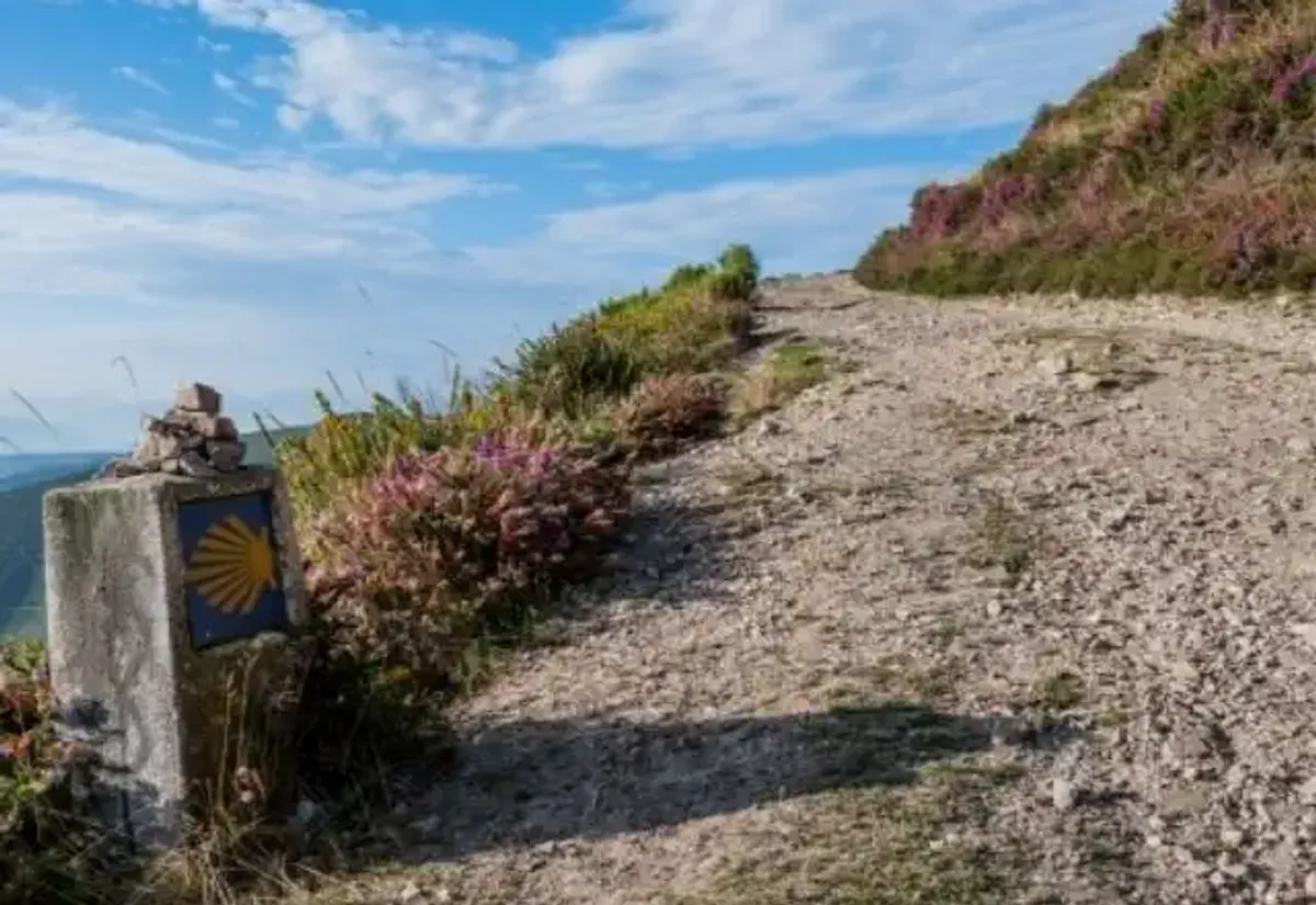 Sendero ascendente junto a un mojón del Camino