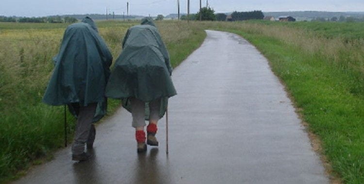 Two pilgrims wearing raincoats in the rain