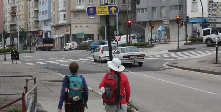 Dos peregrinas mirando una señal del Camino en una calle principal