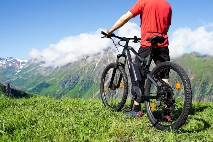 An electric bike and his owner in front of a mountain