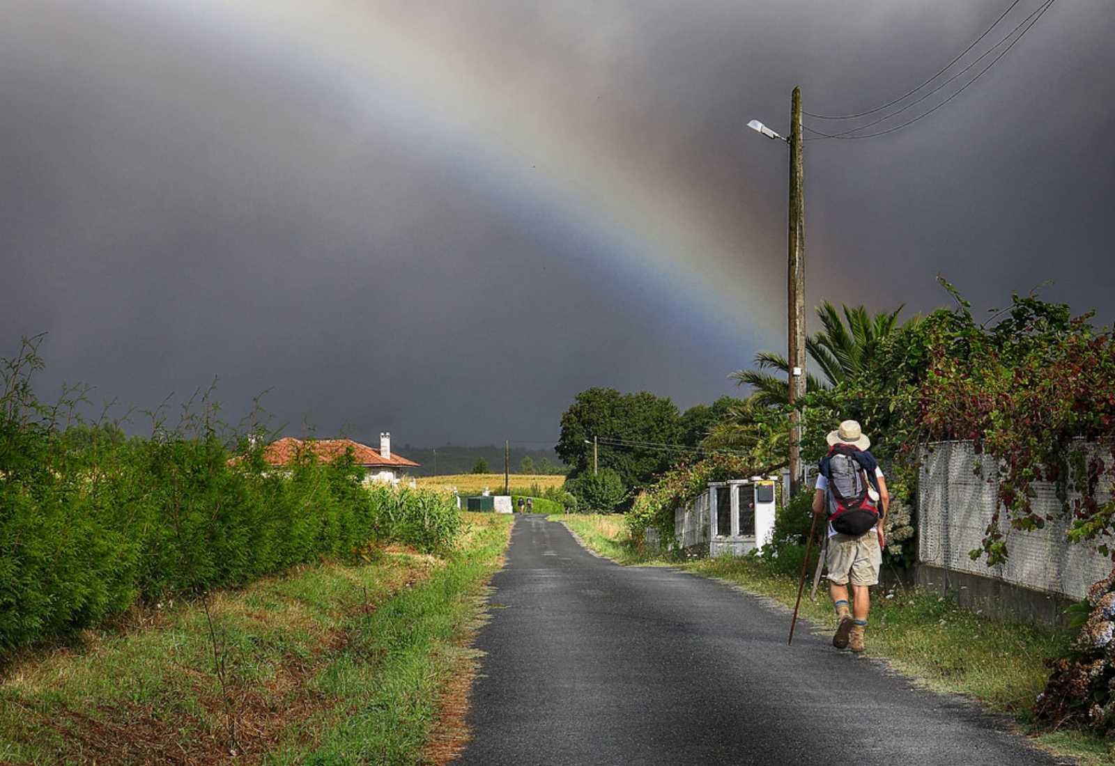 Un peregrino caminando bajo el arcoiris