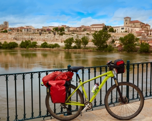 Una bici con alforjas junto a un río