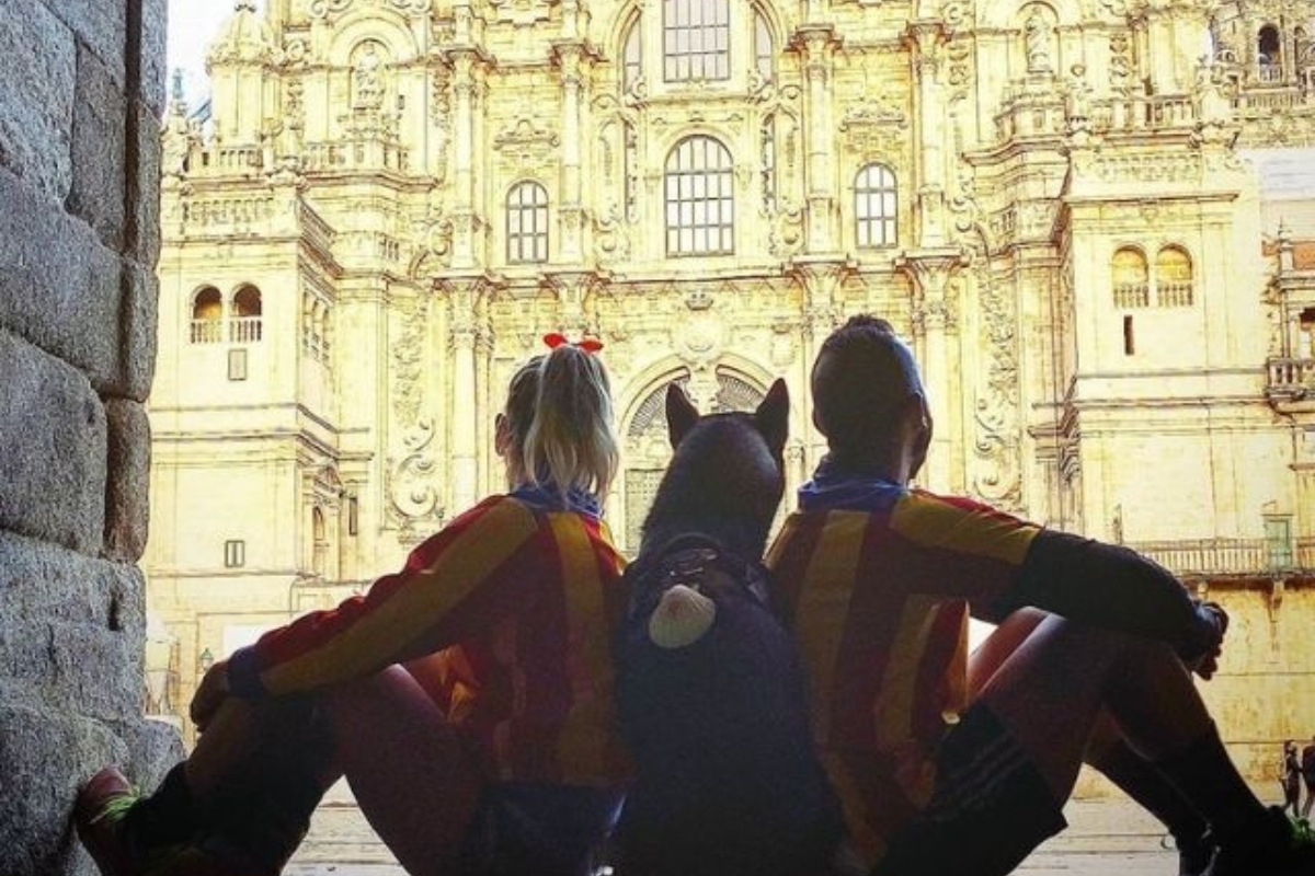 Dos peregrinos con su perro en la plaza del Obradoiro